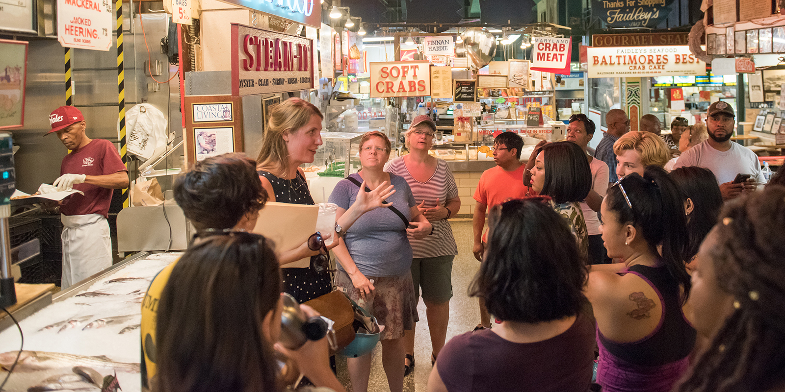 Students gathered around listening to a speaker in Baltimore's Lexington Market.