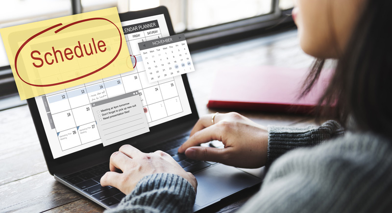 Close-up of a person typing on a computer. The screen has a calendar with a focus on the word 'Schedule'.